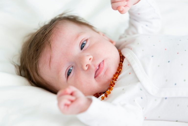 süßes Baby liegend und eine Bernsteinkette tragend