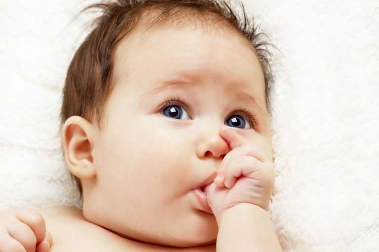 süßes Baby saugt Daumen und schaut auf