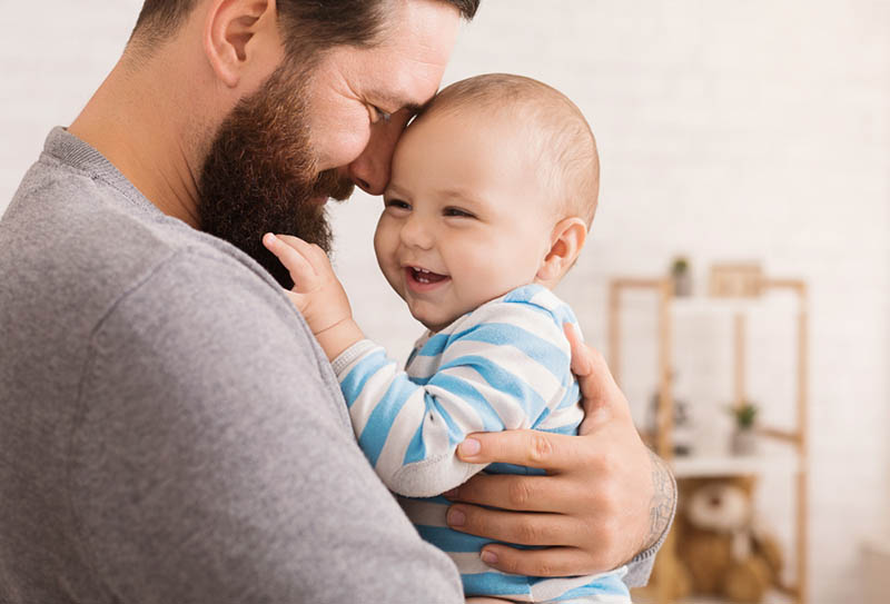 glücklicher Vater kuscheln mit lächelnden niedlichen Baby Junge im Zimmer