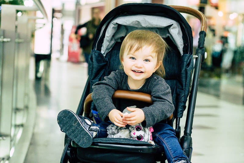 glückliches Baby im Kinderwagen in einem Einkaufszentrum sitzend