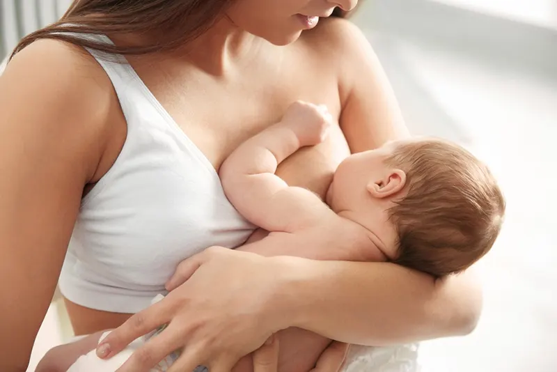 junge Mutter stillt ihr süßes Baby in den Armen