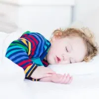 kleiner Junge schläft, während er einen bunten Pyjama trägt