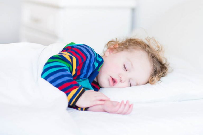 kleiner Junge schläft, während er einen bunten Pyjama trägt