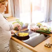 schwangere Frau kocht Rührei in der Küche