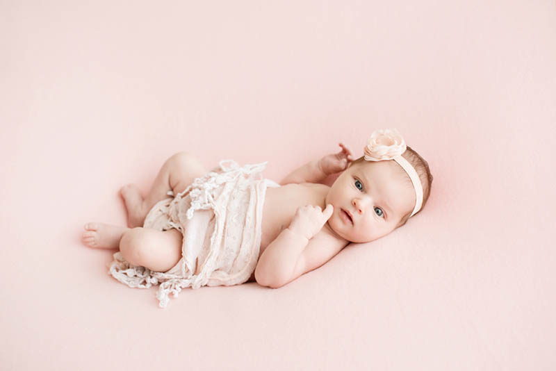 schöne Baby-Mädchen liegt auf dem rosa Blatt für Fotoshooting
