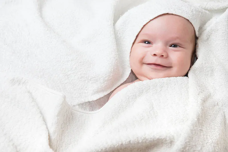 schönes Baby lächelnd voll mit weißem Handtuch bedeckt