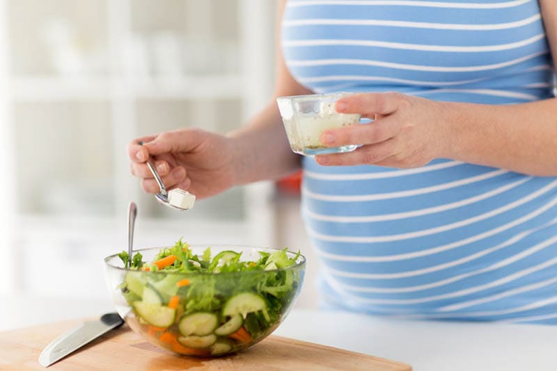 schwangere Frau bereitet einen Salat mit Büffel-Mozzarella-Käse in der Küche