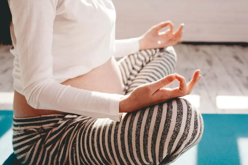 schwangere Frau, die Yoga auf dem Boden zu Hause tut