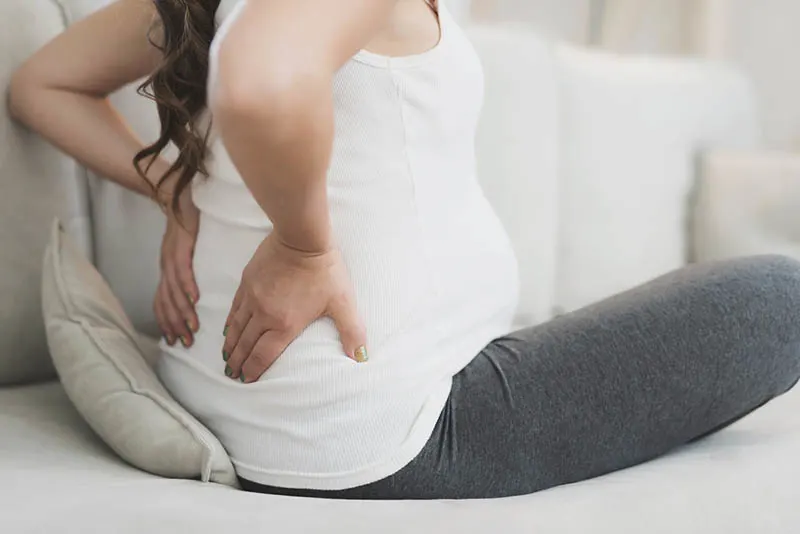 schwangere Frau fühlt Rückenschmerzen und hält für den Rücken