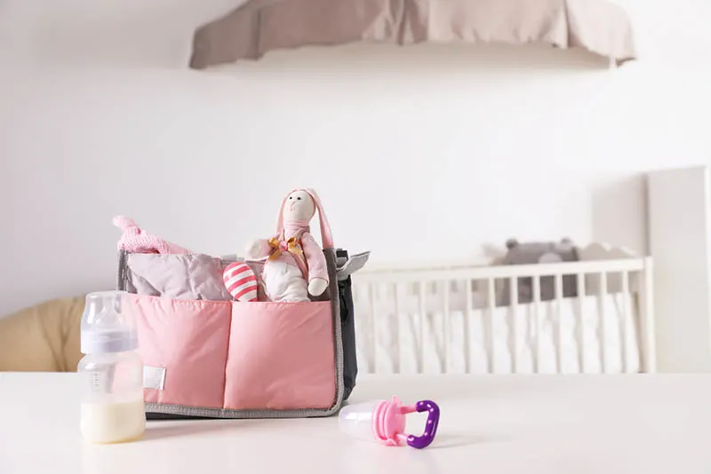 süße Babytasche mit Babyartikeln und Schnuller auf dem Tisch im Babyzimmer