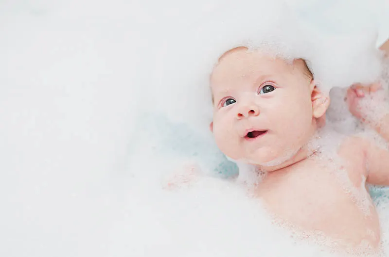 süßes Baby nimmt Bad mit Schaumblasen bedeckt
