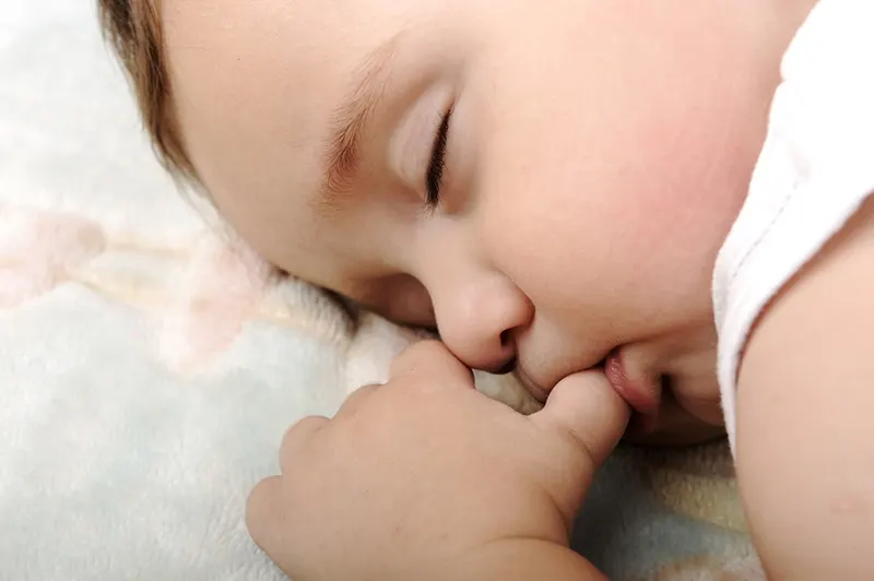 süßes Baby saugt seinen Daumen während des Schlafens