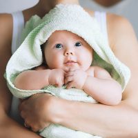 Mutter hält entzückendes Baby in einem Handtuch