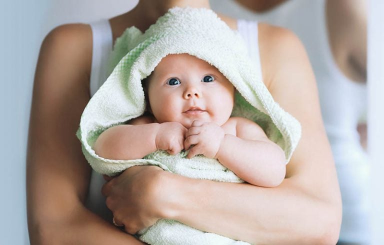 Mutter hält entzückendes Baby in einem Handtuch