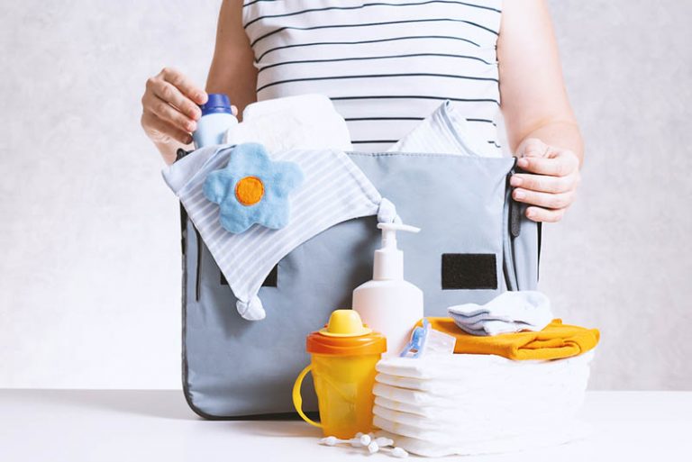 Mutter packt Babywindeltasche mit Babyartikeln