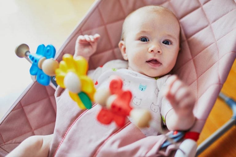 Baby liegt in einer rosa Babywippe