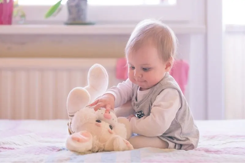10 Monate altes Baby, das mit einem Plüschhasen spielt