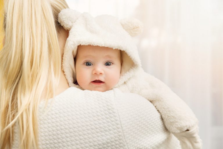 Mutter mit ihrem Baby im flauschigen Bärenkostüm