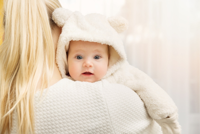 Mutter mit ihrem Baby im flauschigen Bärenkostüm
