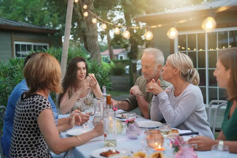 Familie beim gemeinsamen Abendessen im Hof mit schönen Lichtern
