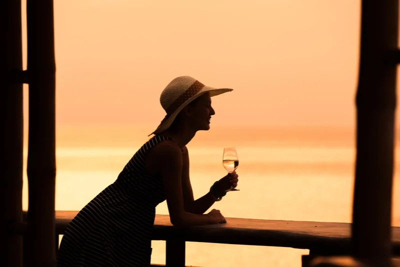 Frau, die die Aussicht und ein Glas Wein genießt.