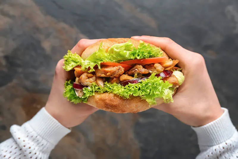 Frau steht im Freien und hält leckeren Döner mit Fleisch, Salat und anderem Gemüse