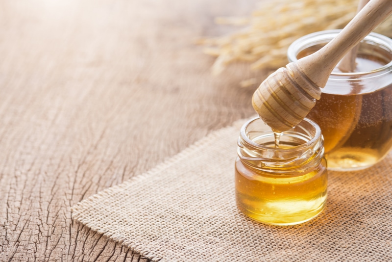 Honig mit hölzernem Honigschöpflöffel auf Holztisch