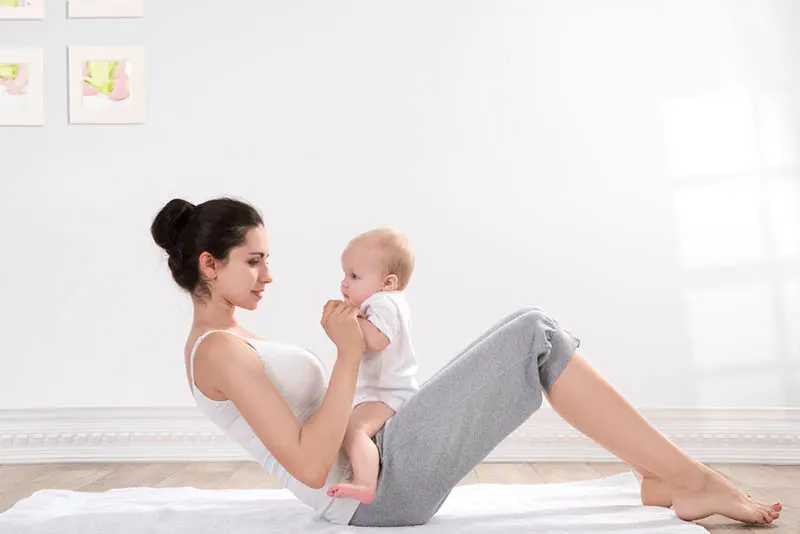 Junge Mutter macht zusammen mit ihrem Baby Fitnessübungen
