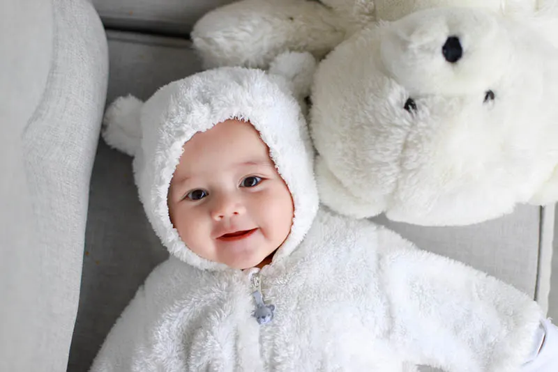 Kleinkind Baby Junge trägt Teddybär Kostüm liegt neben weißen Eisbären