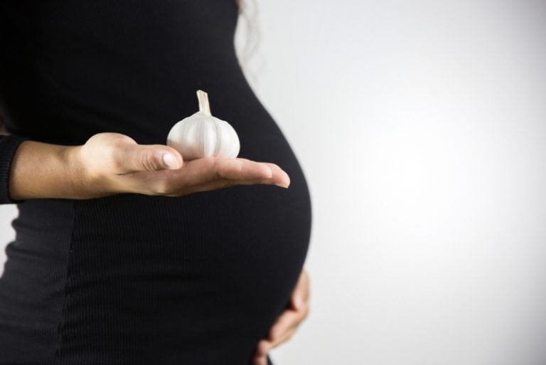 schwangere Frau, die Knoblauch hält