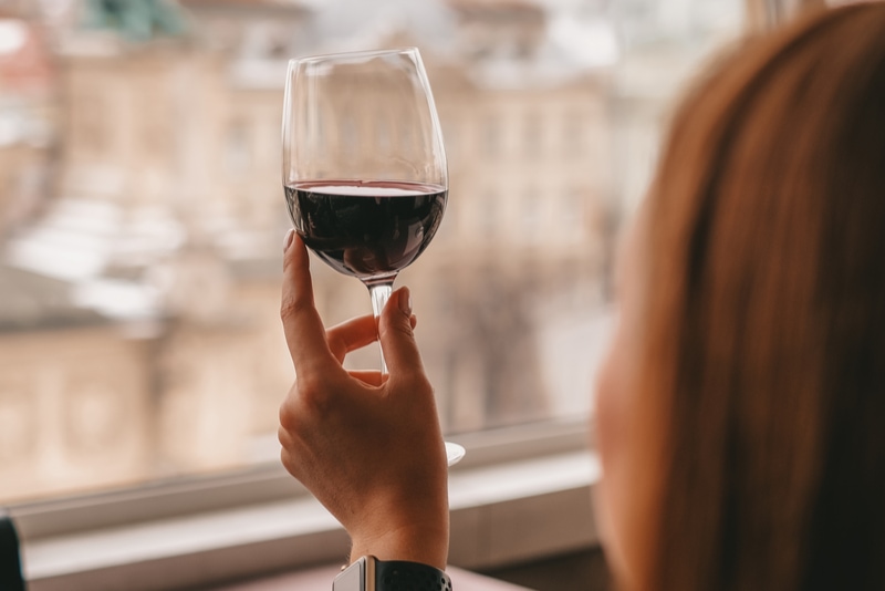 Mädchen in einem Restaurant mit Panoramablick auf die Stadt hält ein Glas Wein