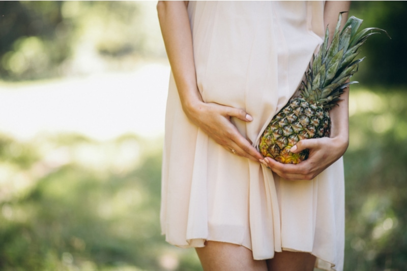 Schwangere Frau, die Ananas hält