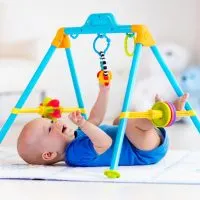 lächelnd Baby Junge spielt mit hängenden Spielzeug in Turnhalle für Babys