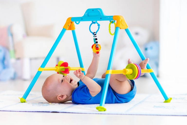 lächelnd Baby Junge spielt mit hängenden Spielzeug in Turnhalle für Babys
