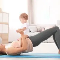 junge Mutter trainiert auf dem Boden mit ihrem Baby