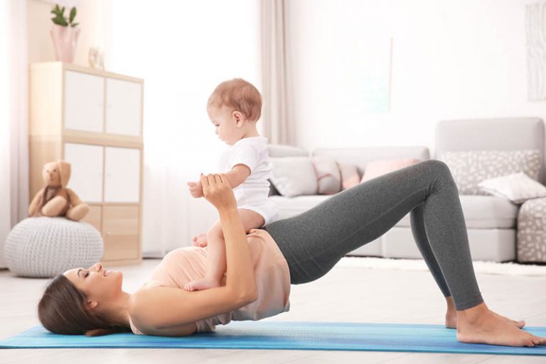 junge Mutter trainiert auf dem Boden mit ihrem Baby