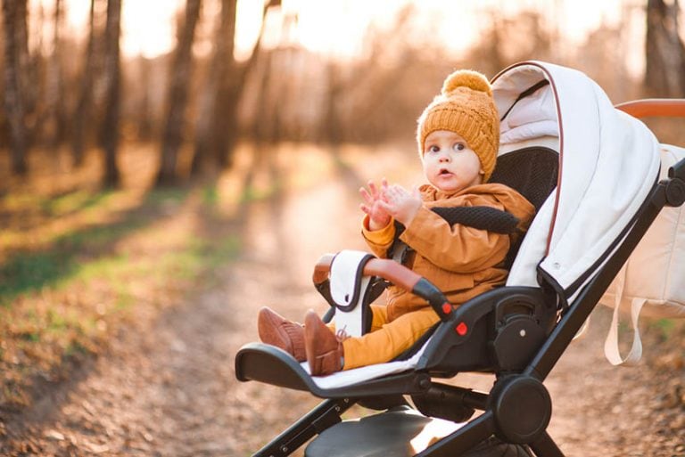 niedlichen Baby Junge sitzt in einem Kinderwagen und trägt Winterkleidung