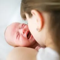Junge Mutter, die versucht, ihr weinendes Neugeborenes zu stillen