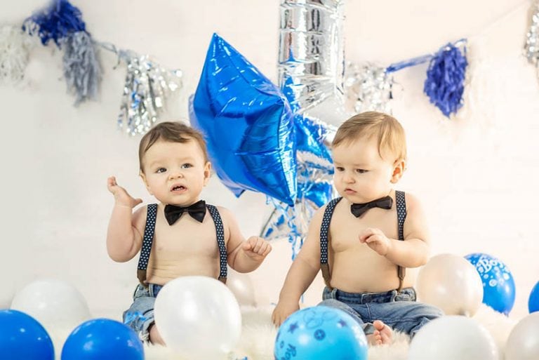 niedlichen Zwillingsbaby Brüder feiern Geburtstag mit Luftballons