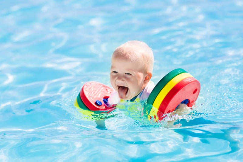 glücklich kleiner Junge schwimmen mit bunten Schwimmern im Pool