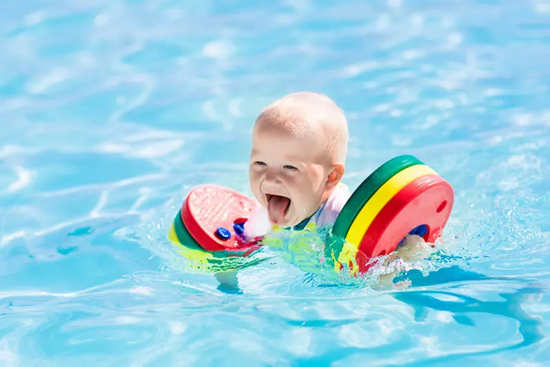 glücklich kleiner Junge schwimmen mit bunten Schwimmern im Pool