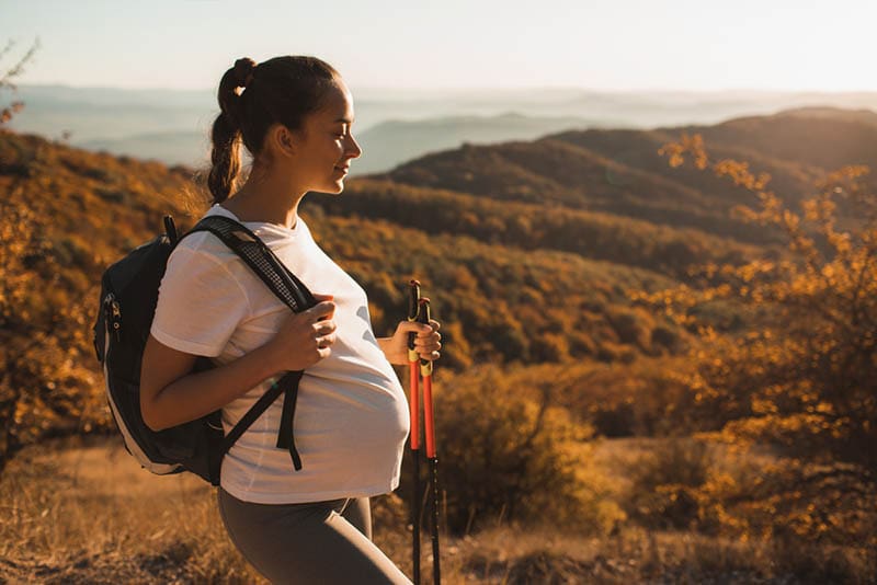 glückliche schwangere Frau beim Wandern in den Bergen
