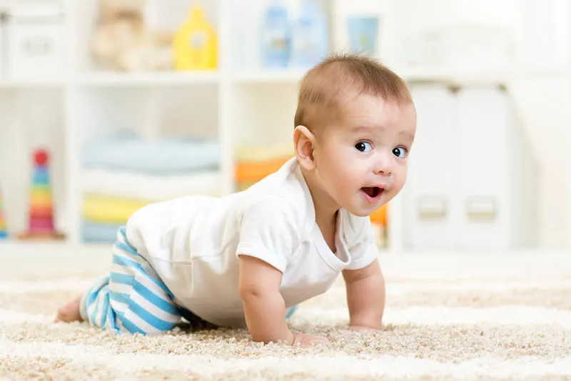 interessanter Babyjunge, der zu Hause auf dem Boden krabbelt