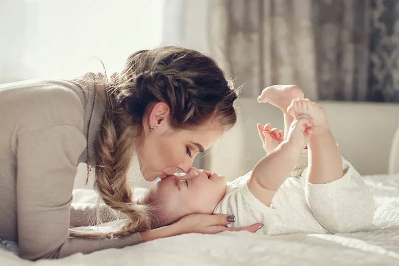 Mutter küsst ihr süßes Baby auf die Stirn