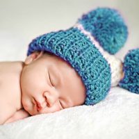 niedlichen Baby Junge schläft mit einem blauen Wintermütze