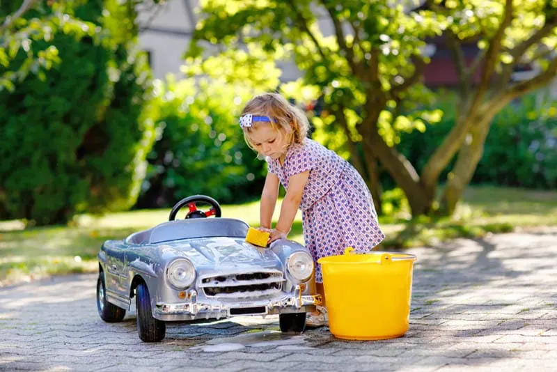 kleines Mädchen wäscht ihr Auto Spielzeug im Freien