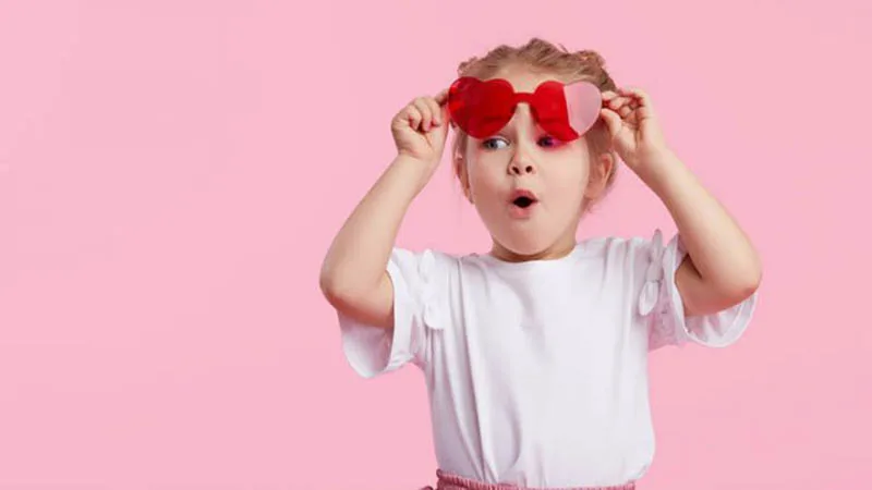 kleines Mädchen zieht rote Sonnenbrille und handeln bewundernd