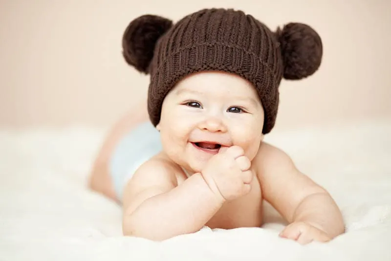 lächelnd Baby Junge trägt braunen Hut und lächelnd auf dem Bett
