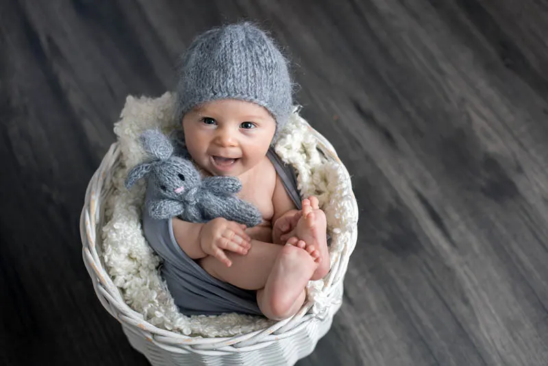 lächelnd Baby posiert in einem Korb mit einem Spielzeug