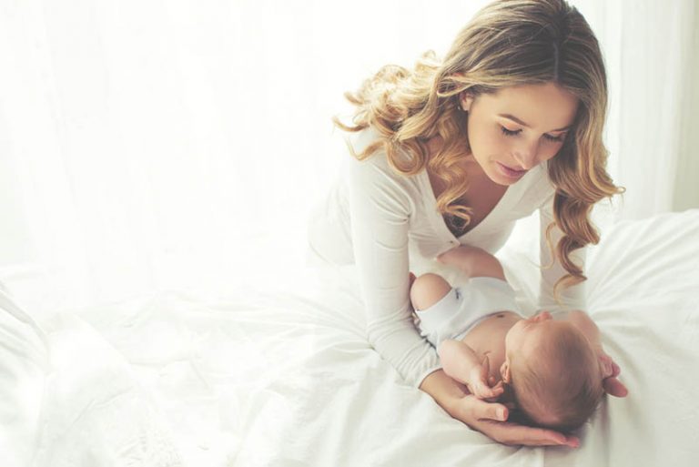 glückliche Mutter hält ihr Baby Sohn auf dem Bett